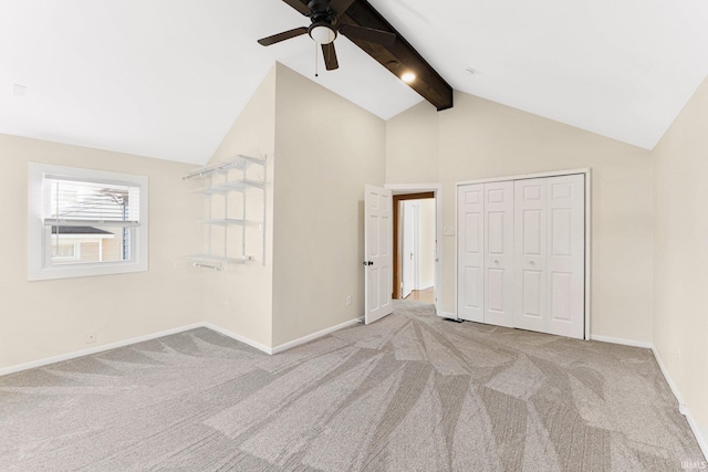 unfurnished bedroom featuring ceiling fan, beam ceiling, a closet, and light carpet