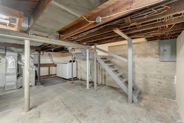 basement with electric panel, washing machine and dryer, and heating unit