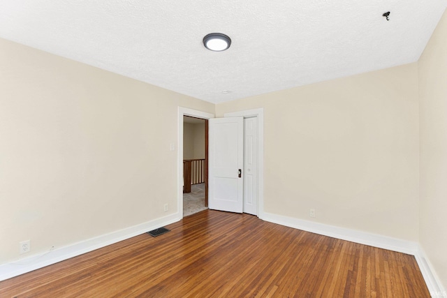 empty room with hardwood / wood-style floors and a textured ceiling