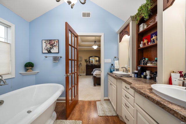 bathroom featuring french doors, wood-type flooring, vaulted ceiling, vanity, and a bathtub