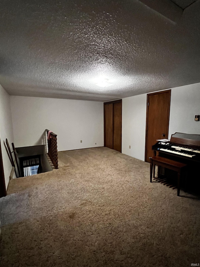 misc room with carpet flooring and a textured ceiling