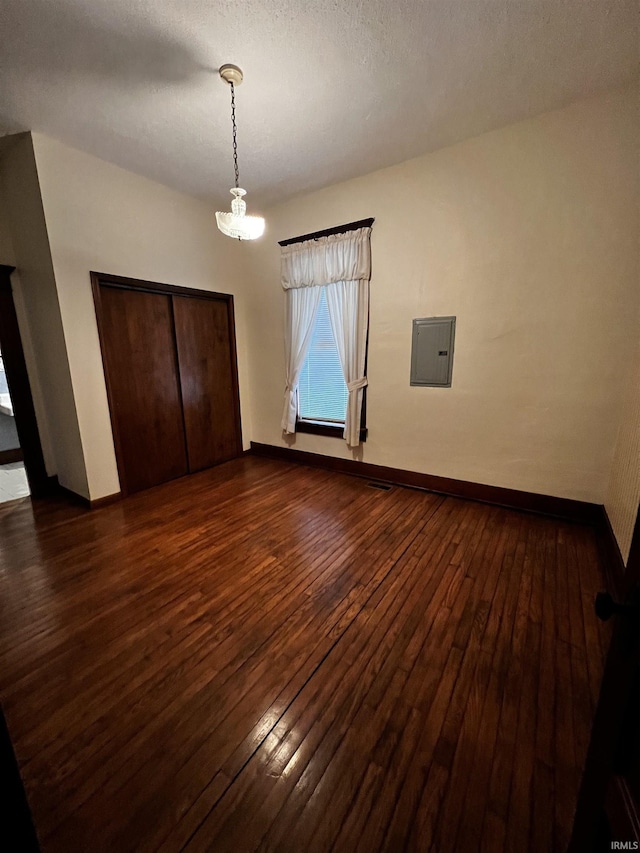 unfurnished bedroom with dark hardwood / wood-style floors, electric panel, and a closet