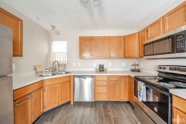 kitchen with stainless steel appliances, sink, and light wood-type flooring