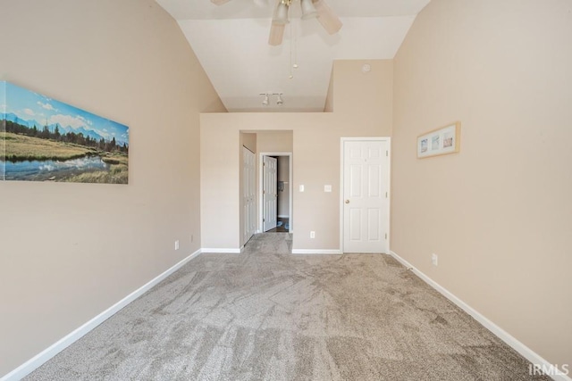 carpeted spare room with ceiling fan and high vaulted ceiling