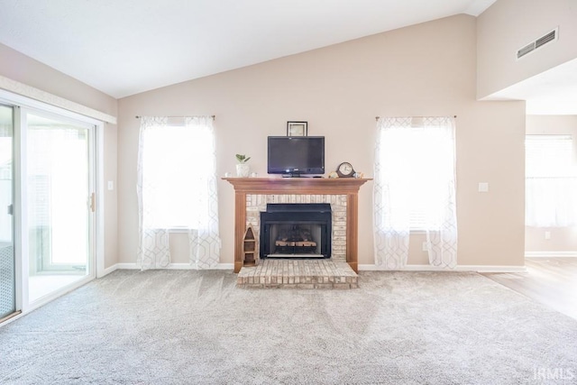 unfurnished living room with vaulted ceiling, a brick fireplace, and light carpet