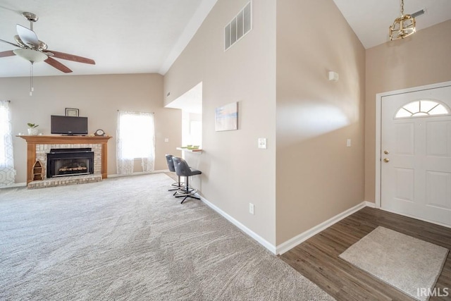 entrance foyer featuring ceiling fan, dark hardwood / wood-style flooring, a fireplace, and high vaulted ceiling