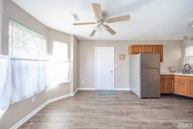 kitchen with stainless steel refrigerator, ceiling fan, light hardwood / wood-style floors, and sink