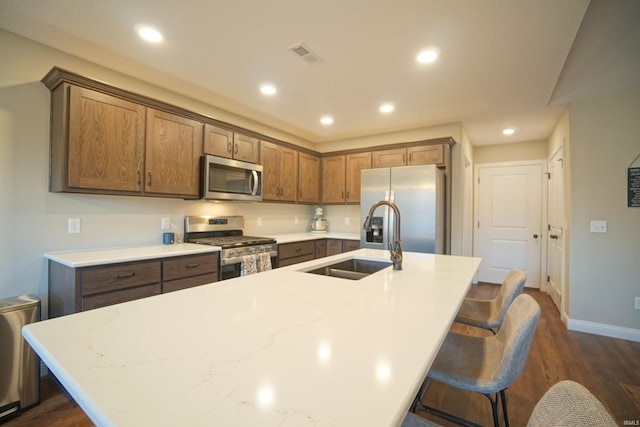 kitchen with sink, stainless steel appliances, a kitchen breakfast bar, and a center island with sink