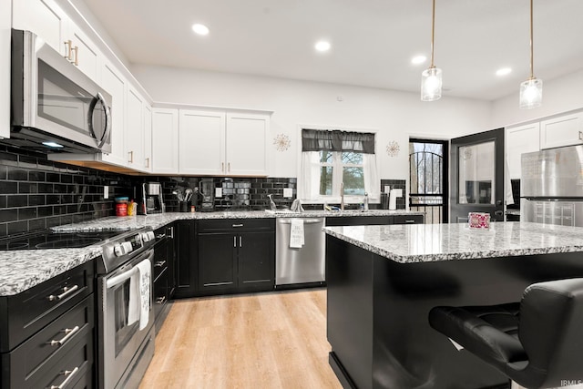 kitchen featuring hanging light fixtures, white cabinetry, appliances with stainless steel finishes, and tasteful backsplash