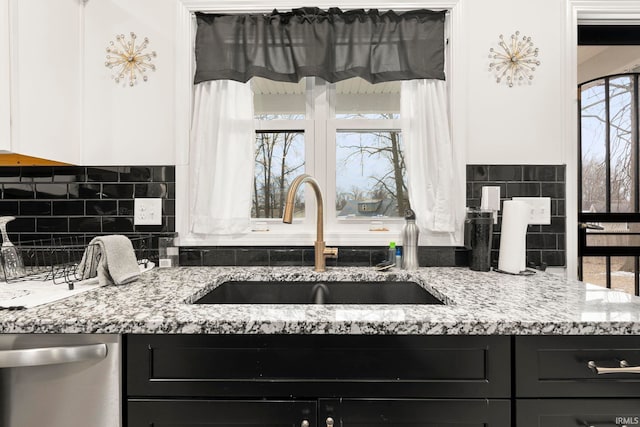 kitchen featuring light stone counters, dishwasher, sink, and white cabinets