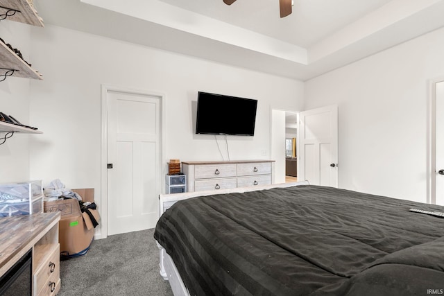 carpeted bedroom with ceiling fan and a tray ceiling