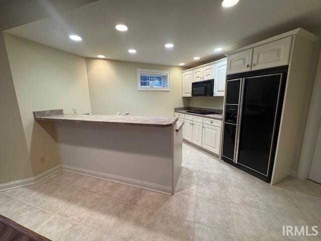 kitchen with white cabinetry, kitchen peninsula, light tile patterned floors, and black appliances