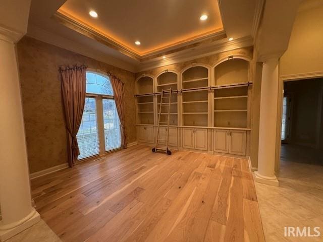 spare room with ornate columns, crown molding, hardwood / wood-style floors, and a tray ceiling