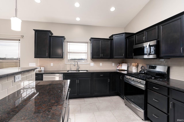 kitchen with hanging light fixtures, stainless steel appliances, sink, and dark stone counters