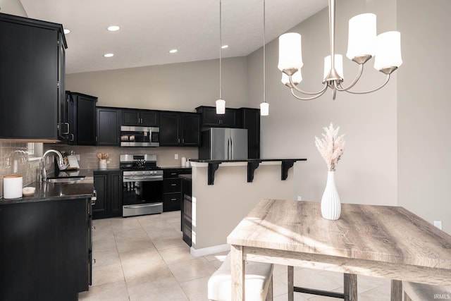 kitchen with sink, appliances with stainless steel finishes, decorative backsplash, a kitchen island, and decorative light fixtures