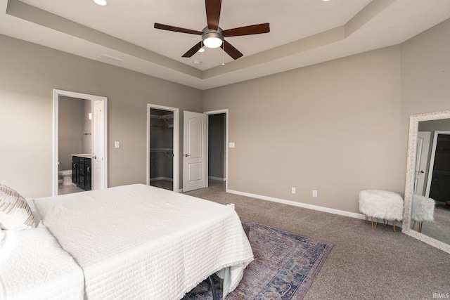 bedroom featuring connected bathroom, a spacious closet, carpet flooring, a tray ceiling, and a closet