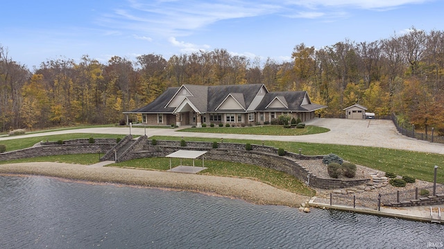 view of front of home featuring a garage, a water view, an outbuilding, and a front yard