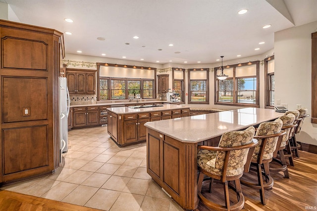 kitchen featuring a spacious island, a healthy amount of sunlight, decorative light fixtures, and stainless steel refrigerator