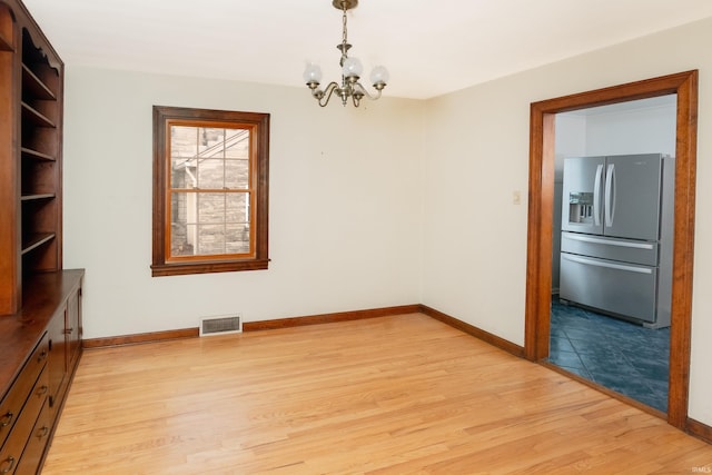 unfurnished dining area featuring a chandelier and light wood-type flooring