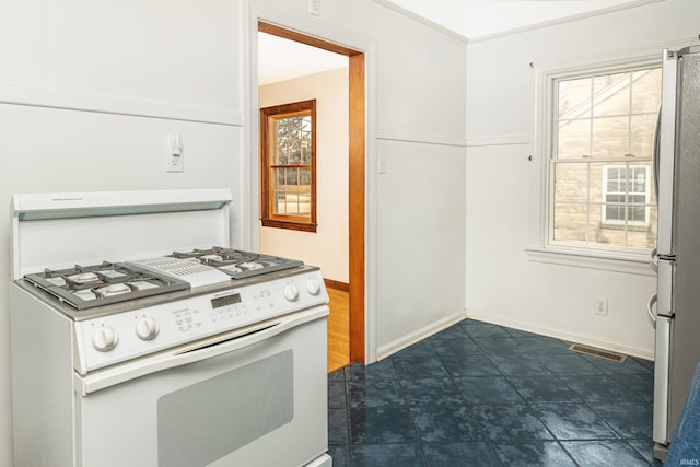 kitchen with white gas range, stainless steel fridge, and plenty of natural light