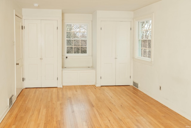 unfurnished bedroom featuring two closets and light hardwood / wood-style floors