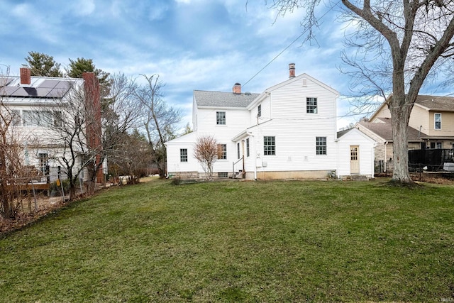 back of property with a lawn and solar panels