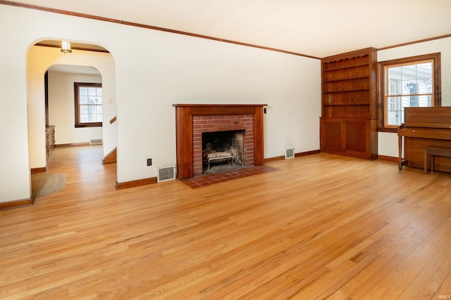 unfurnished living room featuring a fireplace, crown molding, and light hardwood / wood-style flooring