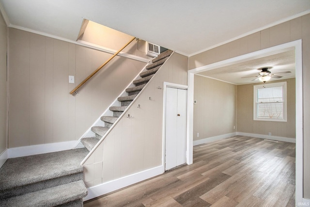 staircase featuring hardwood / wood-style flooring, ornamental molding, and ceiling fan