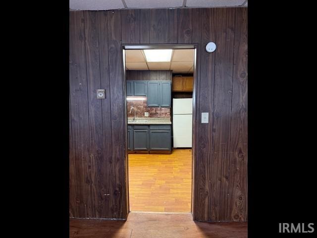 kitchen featuring a paneled ceiling, sink, decorative backsplash, white fridge, and light hardwood / wood-style floors