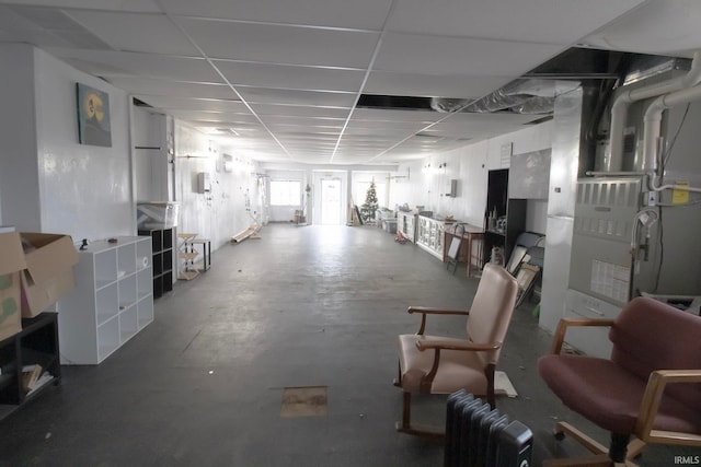 interior space with a drop ceiling, radiator, and concrete flooring