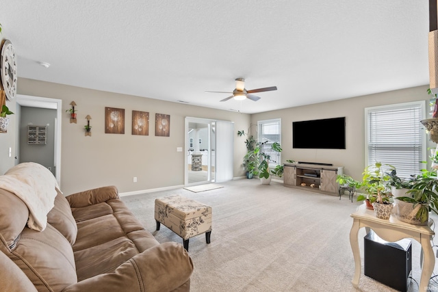 living room with ceiling fan, light colored carpet, and a textured ceiling