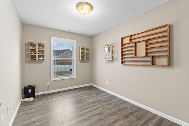 unfurnished room featuring wood-type flooring and a textured ceiling