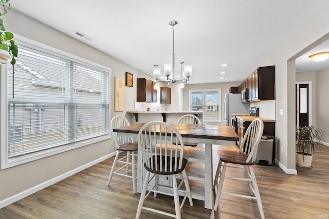 dining area with an inviting chandelier and light hardwood / wood-style flooring