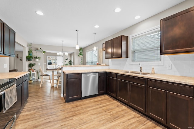 kitchen featuring pendant lighting, sink, light hardwood / wood-style flooring, appliances with stainless steel finishes, and kitchen peninsula