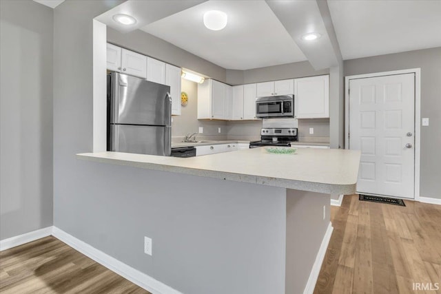 kitchen featuring kitchen peninsula, white cabinets, and appliances with stainless steel finishes