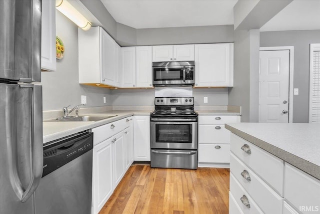 kitchen featuring white cabinetry, appliances with stainless steel finishes, sink, and light wood-type flooring