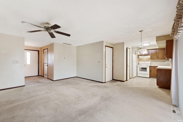 unfurnished living room featuring light colored carpet, sink, and ceiling fan with notable chandelier