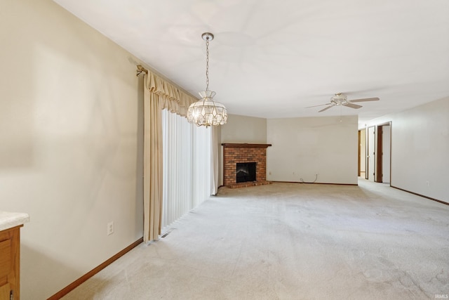 unfurnished living room with light carpet, ceiling fan with notable chandelier, and a fireplace