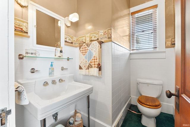 bathroom featuring sink, tile walls, and toilet