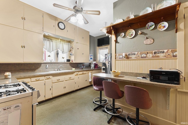 kitchen featuring sink, stainless steel fridge, ceiling fan, a kitchen breakfast bar, and decorative backsplash