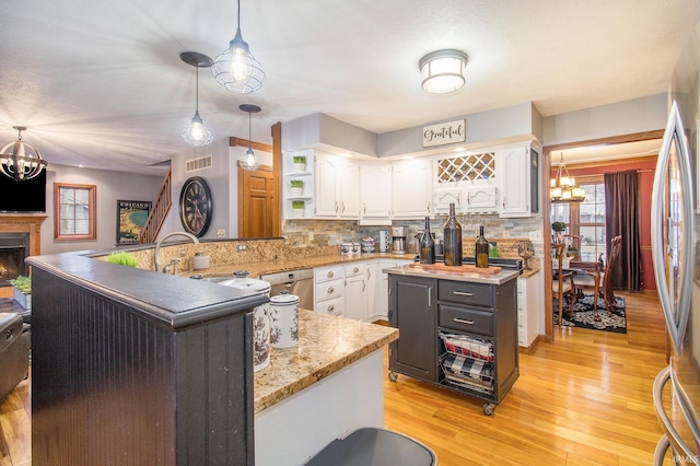 kitchen with sink, white cabinetry, decorative light fixtures, a center island with sink, and a notable chandelier