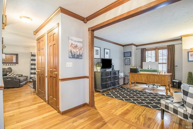 living room featuring light hardwood / wood-style flooring, ornamental molding, and a textured ceiling