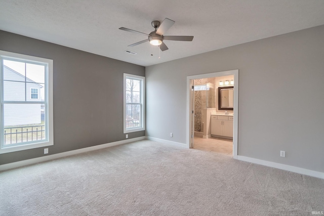 unfurnished bedroom with sink, ceiling fan, connected bathroom, a textured ceiling, and light carpet