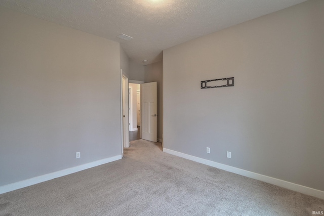 carpeted empty room featuring a textured ceiling