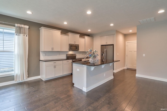 kitchen featuring stainless steel appliances, white cabinetry, a center island, and a kitchen breakfast bar