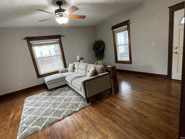 living room with ceiling fan, a healthy amount of sunlight, dark hardwood / wood-style floors, and a textured ceiling