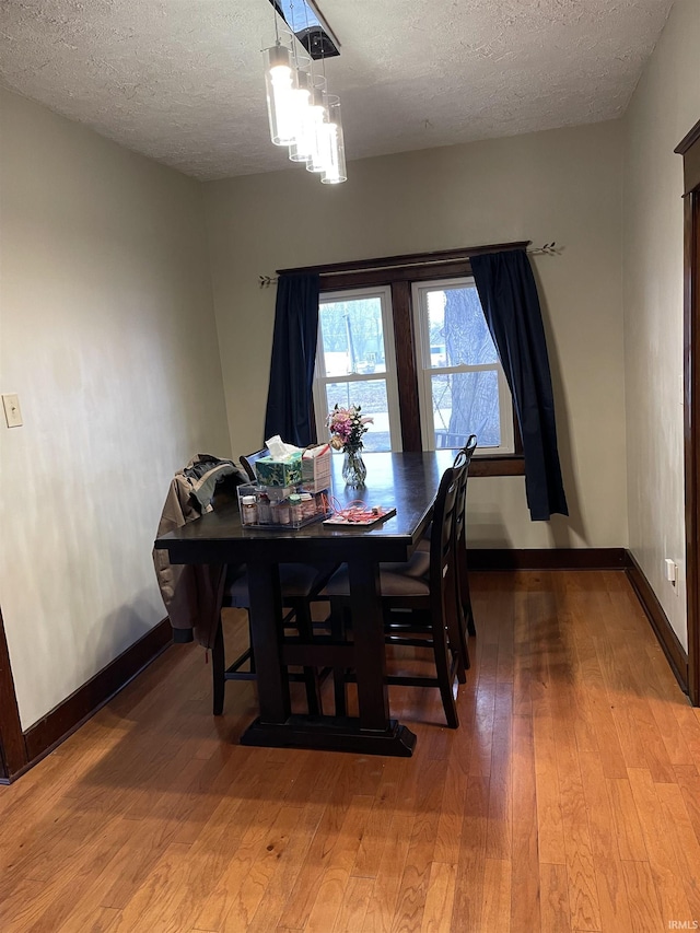 dining space with hardwood / wood-style flooring, an inviting chandelier, and a textured ceiling