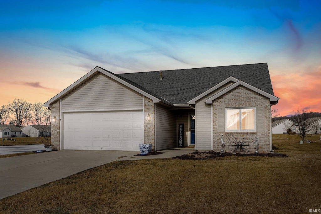 ranch-style home with a garage and a lawn