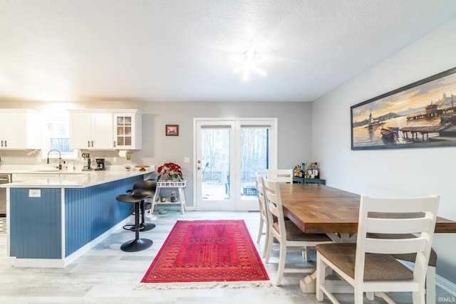 dining space with sink, light hardwood / wood-style floors, and a textured ceiling