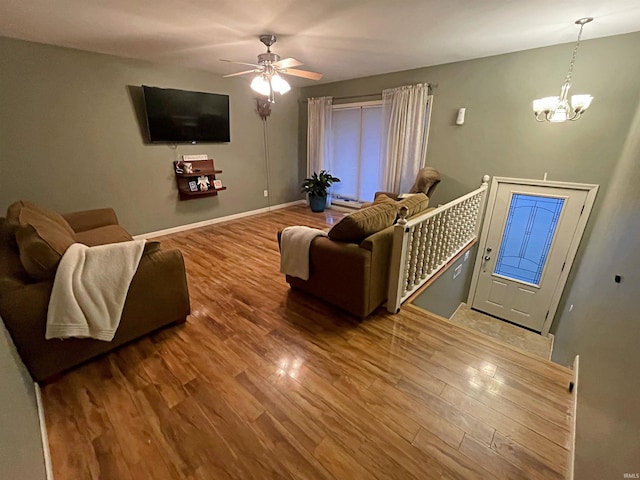 living room with wood-type flooring and ceiling fan with notable chandelier